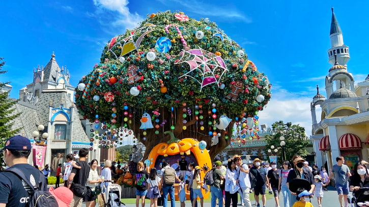 Crowds gather under a Magic tree adorned with ornaments at Everland