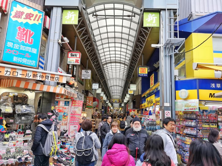 Asakusa's Shin-Nakamise Shopping Street comes alive with a lively scene, featuring colorful stalls and enthusiastic shoppers