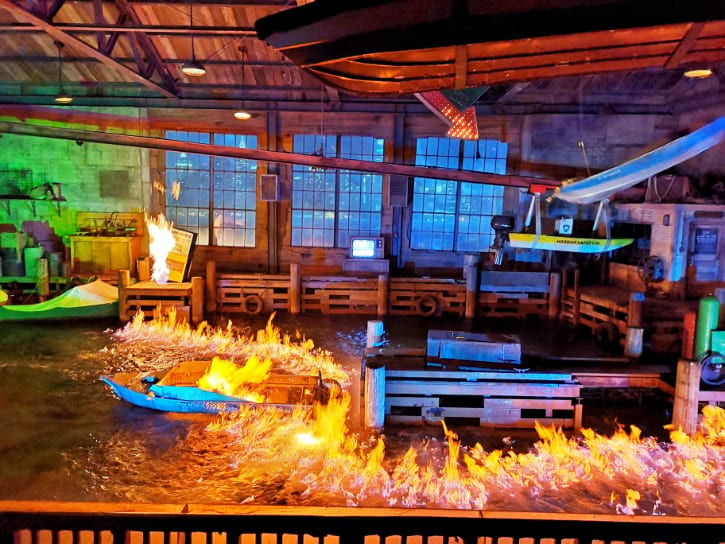 Indoor show simulating a dramatic fiery boat scene with vibrant flames and reflective water