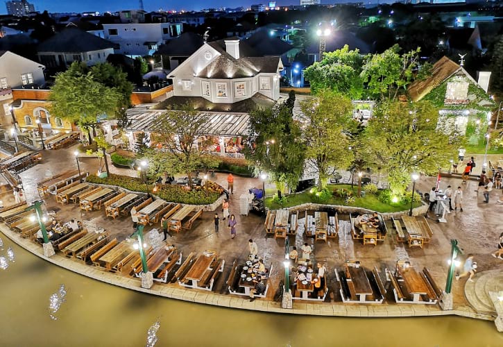 Romantic riverside dining area at Chocolate Ville, Bangkok, with charming lights and serene water views