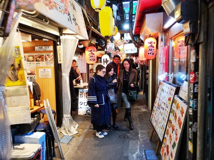 An alley filled with bustling street food stalls and lantern-lit ambiance in Omoide Yokocho