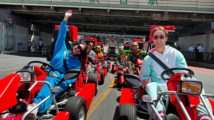 Colorful go-karts driven by people in costumes navigating through the lively streets of Shibuya